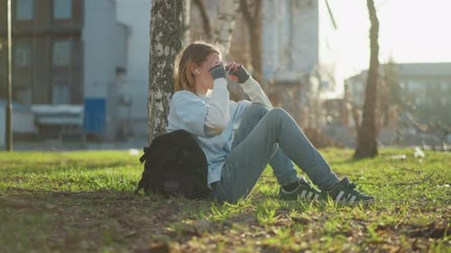 Girl Resting With Backpack By Tree In Park