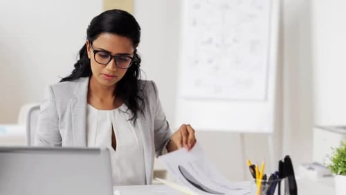 Focused Woman Reviews Documents in Bright Office