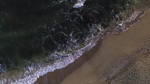 Aerial birdseye view of ocean waves at the beach