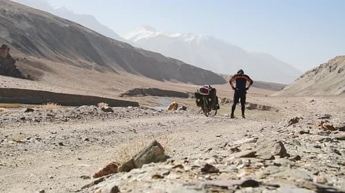 Adventurer with Touring Bike in Remote Desert Valley