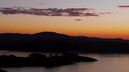 Mountain With Wind Turbines During Sunset With Orange Sky. - aerial shot