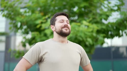 Happy adult sportsman relaxing with closed eyes standing in urban city park alley. Smiling handsome