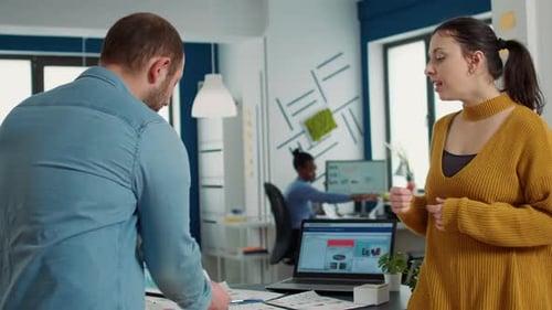 Man in Startup Office Zoomin in Digital Tablet Using Touchscreen Presenting Sales Charts to Woman