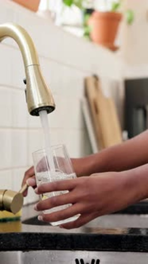Woman Filling Glass of Water at Kitchen Sink