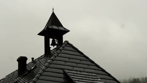 Small Bell Hanging on House Roof Under Cloudy Sky