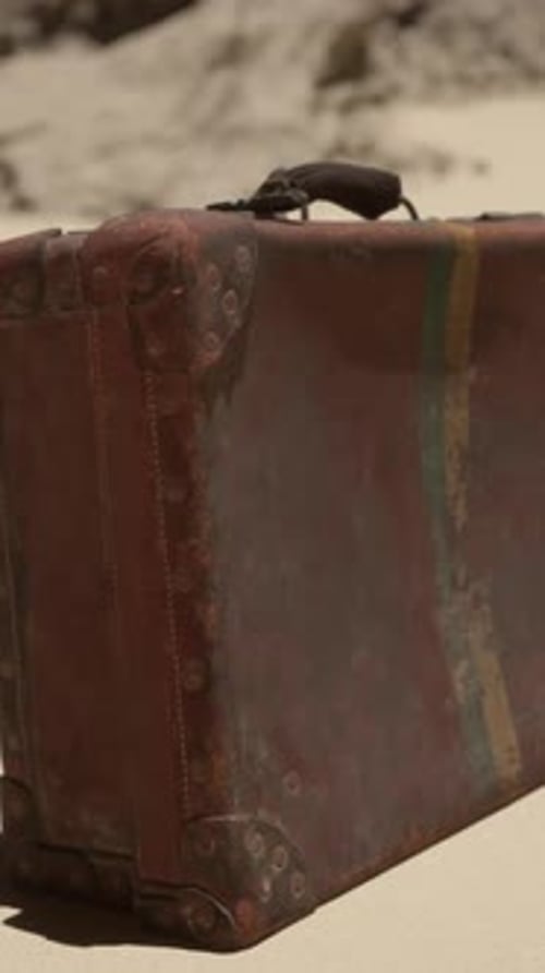 A Piece of Luggage Sitting on Top of a Sandy Beach