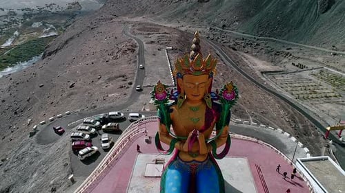 vue aérienne d'une grande sculpture de budha dans une vallée de montagne avec des visiteurs