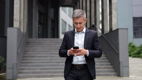 Smiling Businessman in a Suit Walking Outside an Office