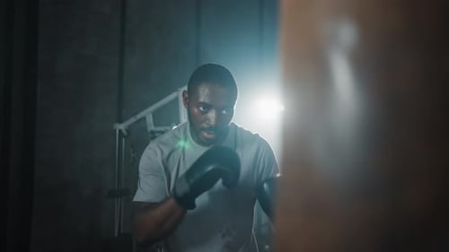 Boxer Training Hitting Punching Bag African American Sweated Sportsman Practicing Punches in Gym