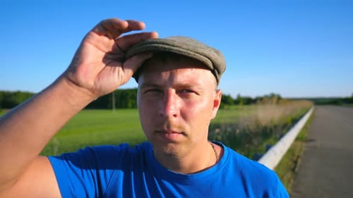 Man Wearing Cap Stands near Rural Field