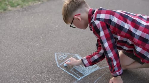 A child draws a dream house on the asphalt with chalk. The concept of buying real estate on credit