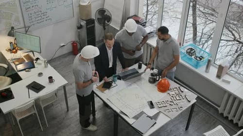 View from above of Engineers Discussing Blueprints in Construction Office