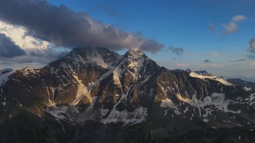 A Stunning Aerial View of Snowcovered Mountains with Clouds in the Sky