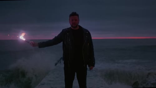 Man Holding Torch Standing on Pier in Ocean