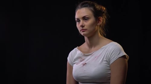 Bruised Woman Looking Down Sadly in Dark Studio