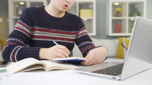Young Adult Studying and Taking Notes at Desk