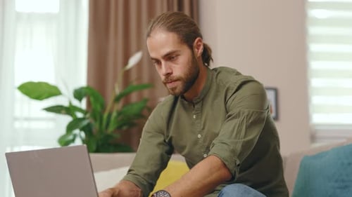 Man Works on Laptop from Couch
