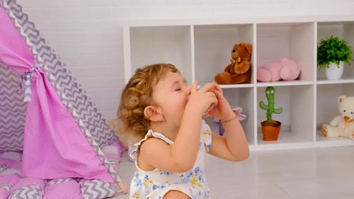 Cute Child Drinking From Jar in Playroom