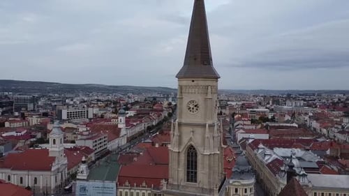 Vista aérea de uma cidade histórica com uma alta torre de igreja em estilo gótico com um relógio. O entorno