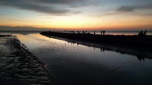 Avancez lentement vers les gens qui se rassemblent dans la baie, admirez la beauté des paysages du coucher du soleil.