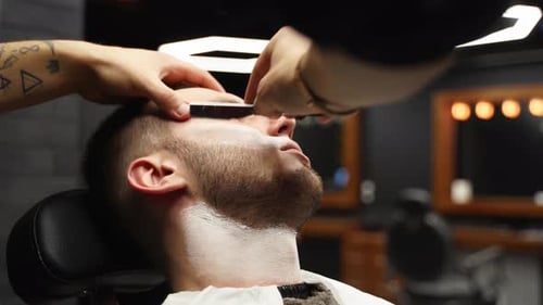 Barber Shaving Man with Straight Razor at Barbershop