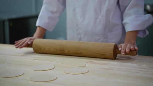 Baker Rolls Dough with Rolling Pin in Kitchen