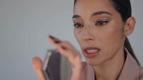 Attractive young woman applying lip gloss, makeup tutorial