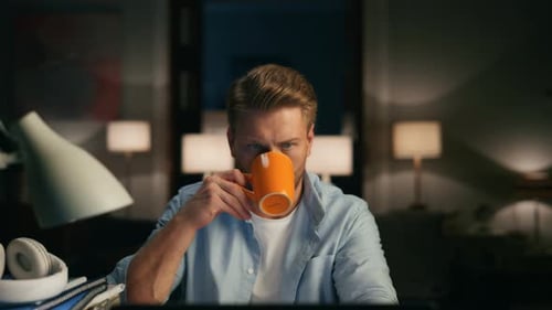 Man Working Late at Desk with Laptop and Coffee