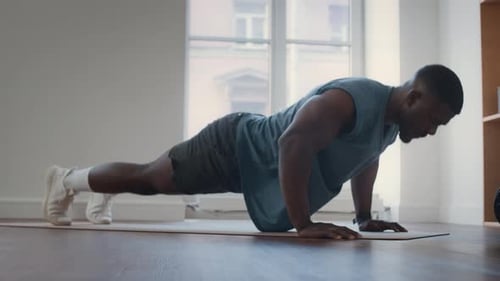 Athletic Black Man Doing Push-Ups on Exercise Mat in Home Gym