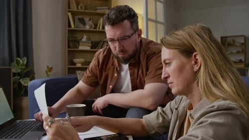 Couple reviews bills and laptop in their home