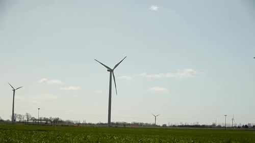Wind turbines standing tall in a lush green field under a clear blue sky
