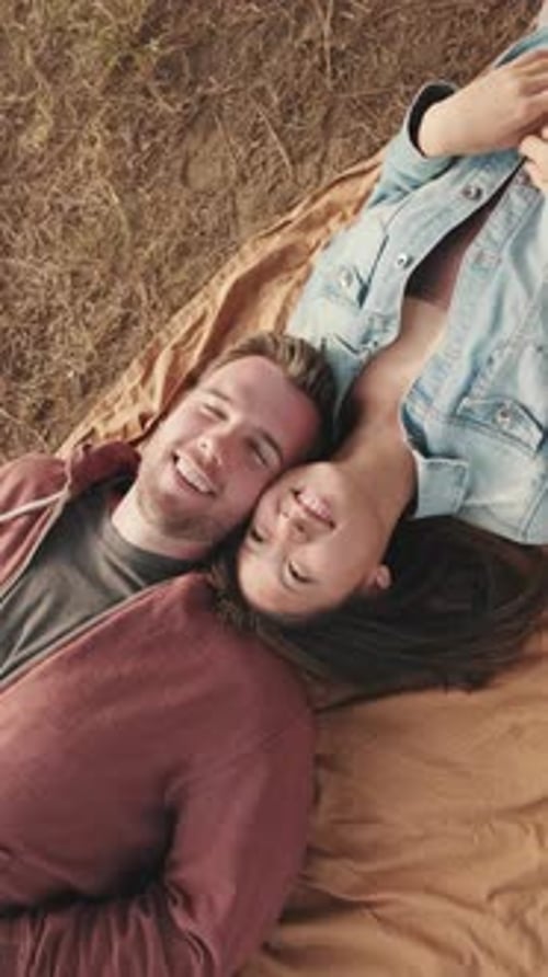 Close-up of young couple lying on blanket in the park from outside
