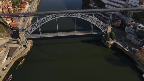 Aerial view of the top of a metal bridge that crosses a river with a city on both sides