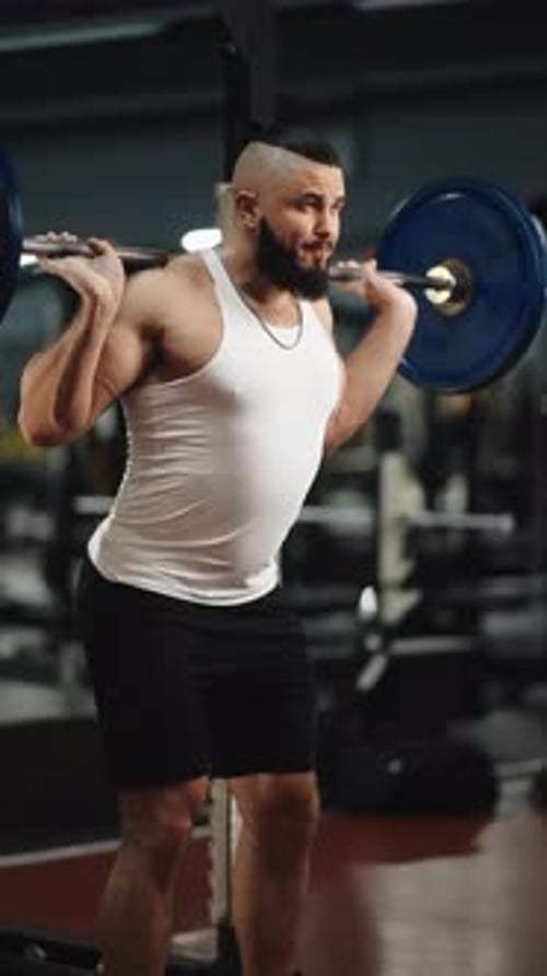 Muscular Man Lifting Heavy Barbell During Intense Leg Workout Straining Muscles in Professional Gym