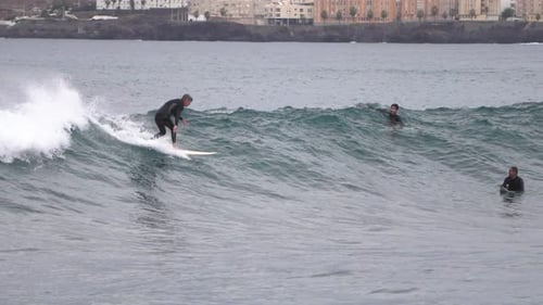 Surfer ride waves in slow motion at Las Canteras beach in Las Palmas de Gran Canaria, Spain.