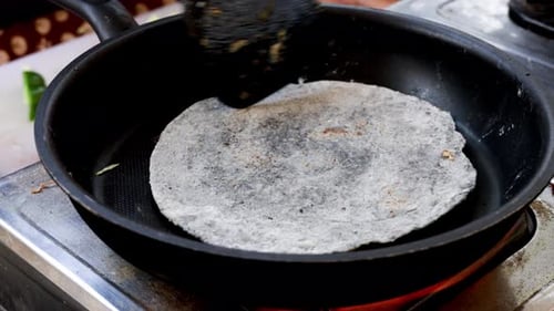 Cooking chicken taco series: Street food vendor grilling and flipping a flour tortilla in a frying p