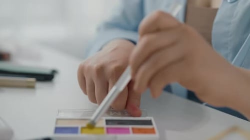 Closeup View of Young Lady Hands and Bright Eyeshadow Palette in Beauty Studio Professional Makeup