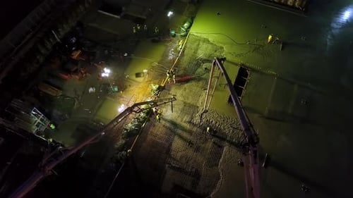 Sitio de construcción industrial por la noche, cimentación del edificio en funcionamiento con grúa