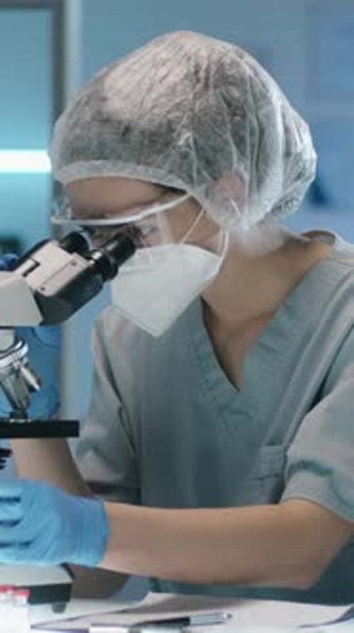 Lab Worker Using Microscope in Medical Setting