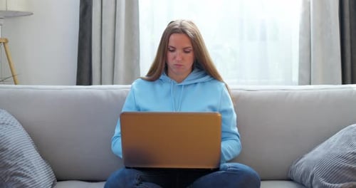 Woman Works on Laptop Sitting on Sofa