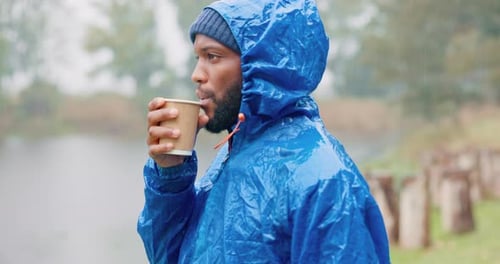 Young Adult Drinks from Cup in the Rain
