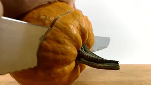 Carving pumpkin part 1, Person cutting off the top of Halloween pumpkin with a large serrated knife
