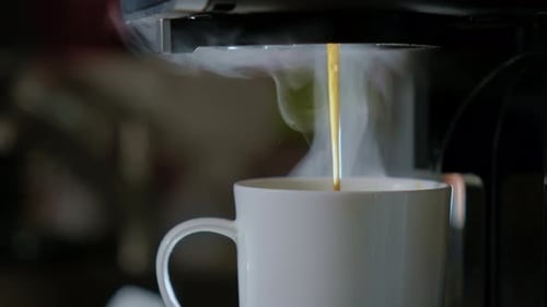 Close Up View of Hot Black Coffee Pouring From the Machine to White Cup Fresh Cafe in the Kitchen of