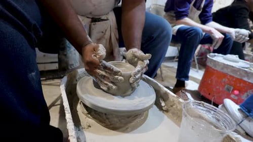 overhead close view of an African American hands spinning clay very sporadically while taking a pott
