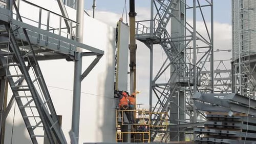 Bauarbeiter montieren eine Betonwand Ein Baukran hebt eine Betonwand - Arbeit und Bau
