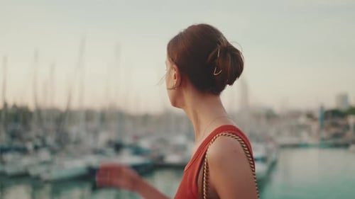 Close-up, girl stands on the seashore and looks at the bay and fixes her hair