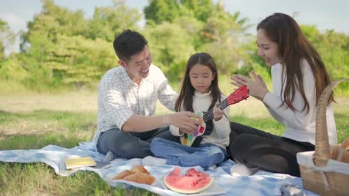 Family Plays Ukulele During Sunny Picnic Outdoors