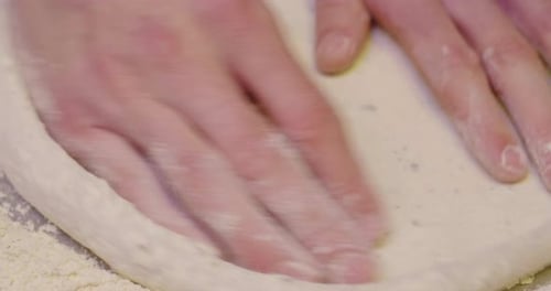 Close up of a pizza chef's hands kneading the dough to prepare a gourmet pizza and spreads the tom