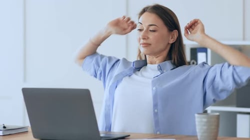 Woman Stretching at Her Desk in an Office