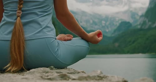 Close-up of a woman hands in a meditative pose with a mountain lake background